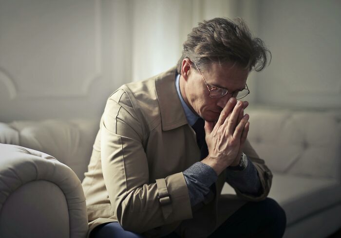 Middle-aged man in a jacket sitting on a sofa, looking thoughtful and reflecting on life after losing an amazing partner.