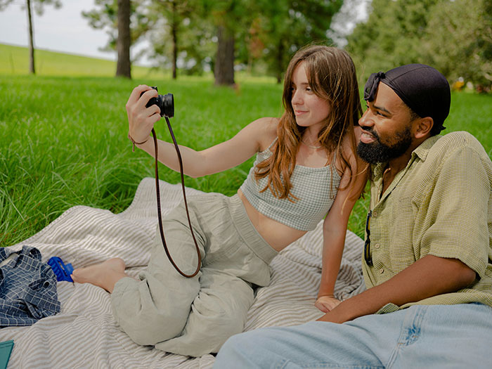 Couple enjoying a picnic outdoors, taking a selfie together, sharing moments of dating a famous actress.