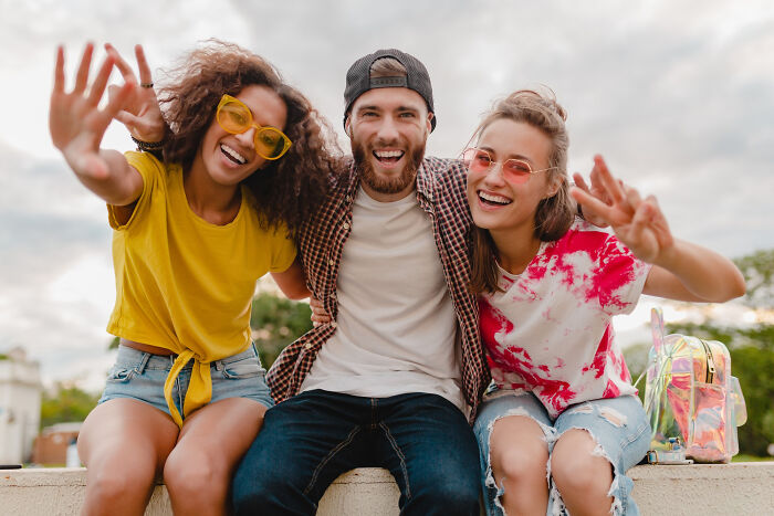 Three young friends smiling and posing outdoors, highlighting attention-seeking and childhood habit red flags.