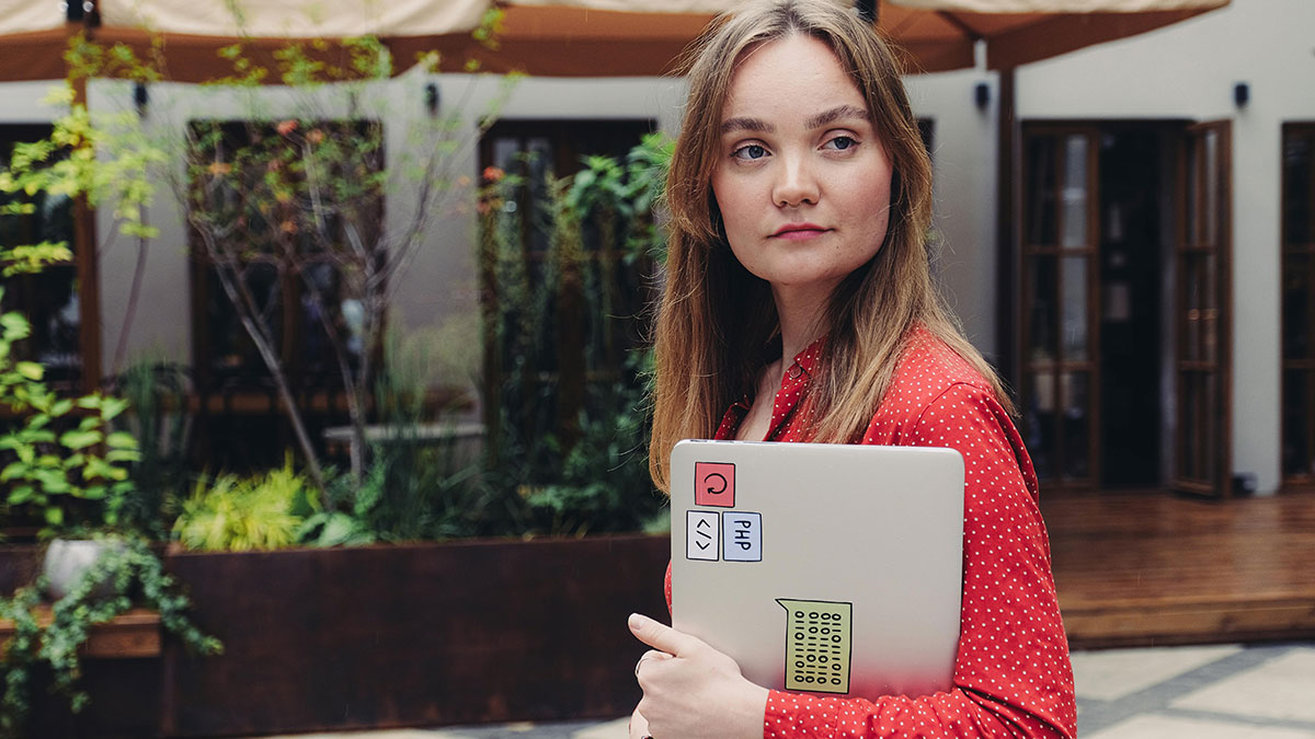 Young woman holding laptop outdoors, symbolizing attention-seeking and childhood habits as potential red flags.