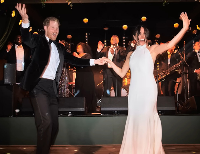 Prince Harry and Meghan Markle dancing joyfully at an event with a live band performing on stage behind them. Prince Harry and Meghan Markle dancing joyfully at an event with a live band performing on stage behind them.