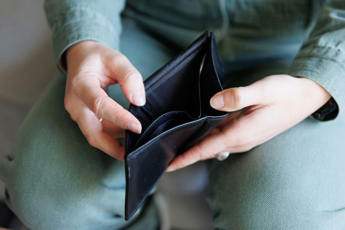 Woman holding empty black wallet, representing refusal to help with debts and sister conflict over money. Woman holding empty black wallet, representing refusal to help with debts and sister conflict over money.