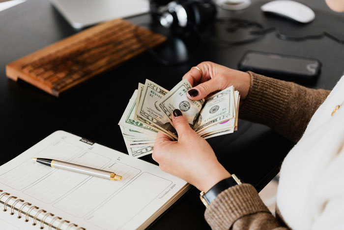 Woman counting cash and managing debt payments at desk, illustrating family financial disputes and refusal to help. Woman counting cash and managing debt payments at desk, illustrating family financial disputes and refusal to help.