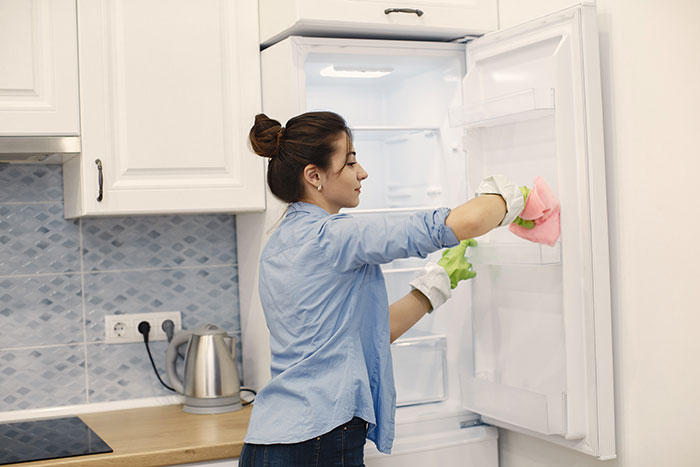 Woman cleaning the inside of a refrigerator, representing a wife’s cleaning triggering a husband’s meltdown over olives. Woman cleaning the inside of a refrigerator, representing a wife’s cleaning triggering a husband’s meltdown over olives.