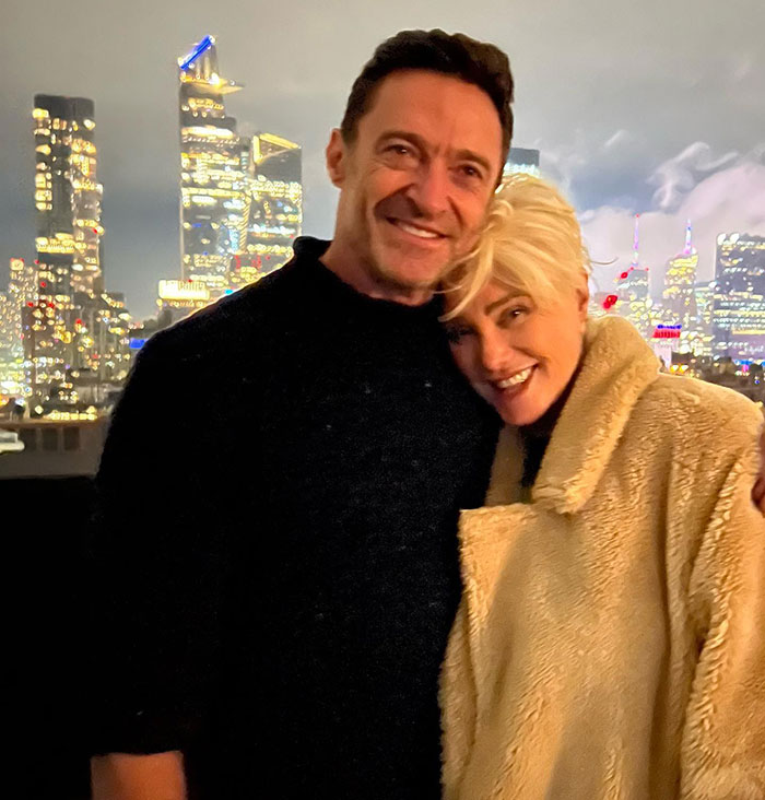 Hugh Jackman and Sutton Foster smiling together outdoors at night with city lights in the background. Hugh Jackman and Sutton Foster smiling together outdoors at night with city lights in the background.