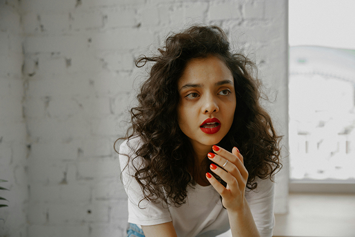 Woman with curly hair and red lipstick looking surprised during an awkward birthday dinner pregnancy stunt moment. Woman with curly hair and red lipstick looking surprised during an awkward birthday dinner pregnancy stunt moment.