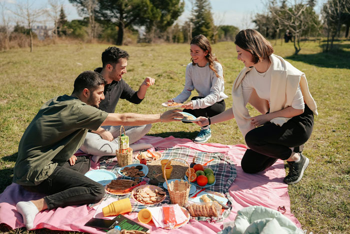Four young adults enjoying a casual outdoor picnic, highlighting a 28YO with his 21YO work buddy and girlfriend. Four young adults enjoying a casual outdoor picnic, highlighting a 28YO with his 21YO work buddy and girlfriend.