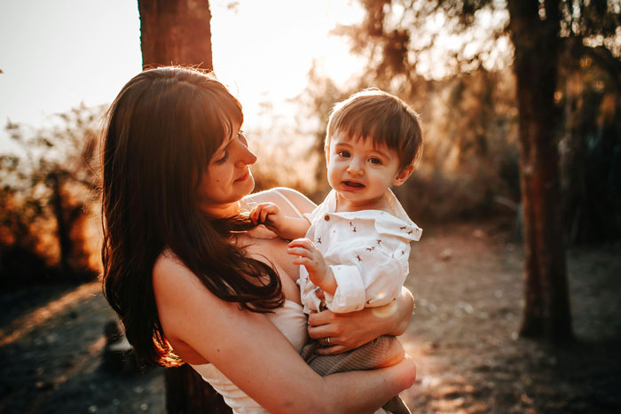 Woman holding toddler outside at sunset, capturing a warm moment, linked to 28YO wanting to hang out with work buddy. Woman holding toddler outside at sunset, capturing a warm moment, linked to 28YO wanting to hang out with work buddy.