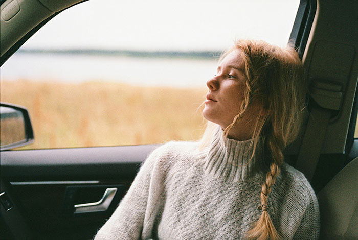 Woman with braided hair in a car, looking thoughtfully outside window during a cross-country move and emotional moment. Woman with braided hair in a car, looking thoughtfully outside window during a cross-country move and emotional moment.