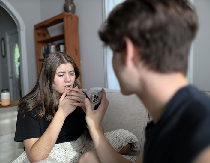 Woman looks shocked while her husband holds a phone, depicting a tense moment after being hit on for the first time.