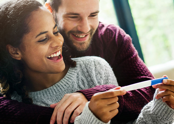 Woman surprises husband with pregnancy test as gift, both smiling and sharing a joyful moment at home. Woman surprises husband with pregnancy test as gift, both smiling and sharing a joyful moment at home.