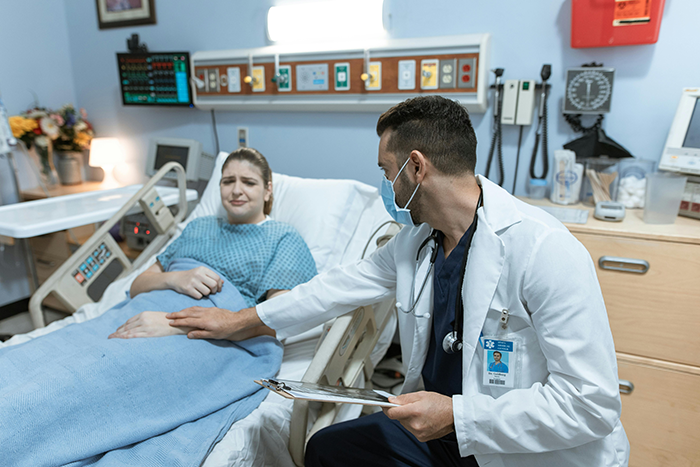 Doctor in white coat comforting woman in hospital bed after cancer diagnosis impacting biological kids and family relations Doctor in white coat comforting woman in hospital bed after cancer diagnosis impacting biological kids and family relations