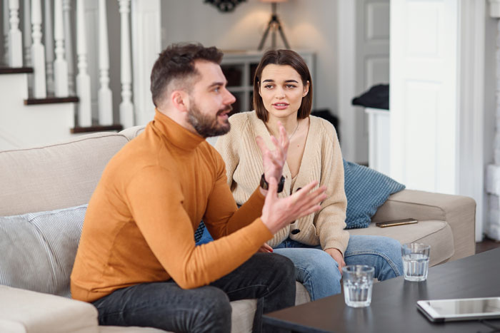 Couple having a serious conversation on a couch as woman tells fiancé his gaming days are over. Couple having a serious conversation on a couch as woman tells fiancé his gaming days are over.