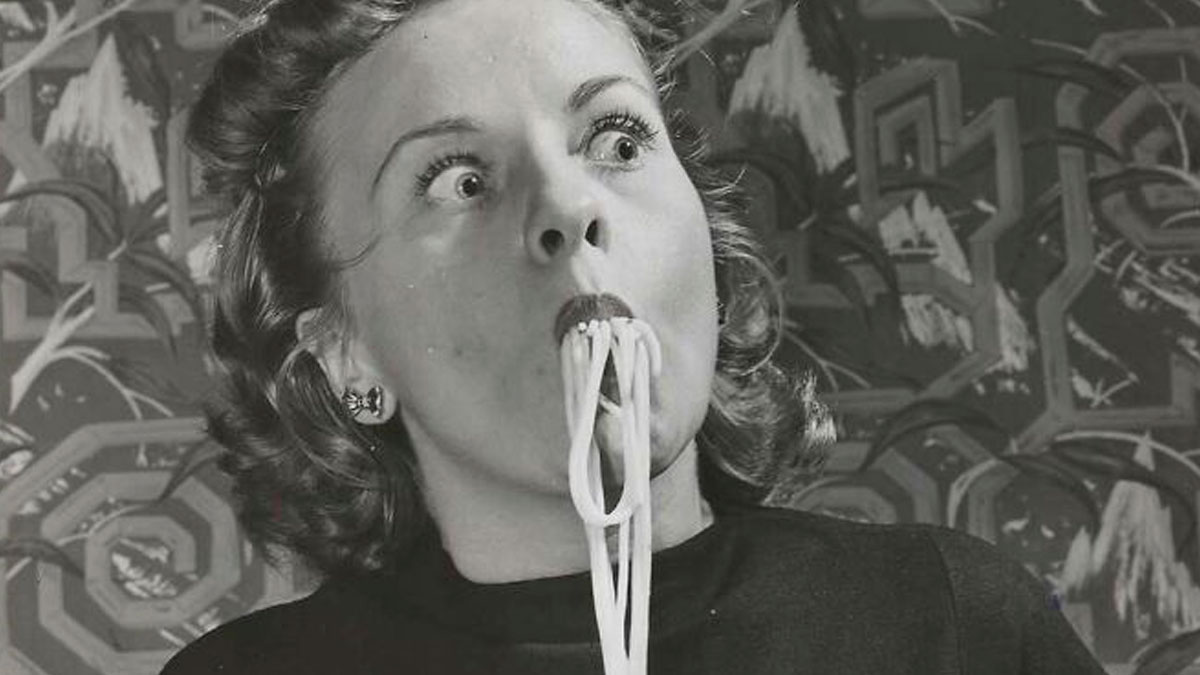 Black and white vintage photo of a woman eating spaghetti with an exaggerated expression showcasing mesmerizing history moments.