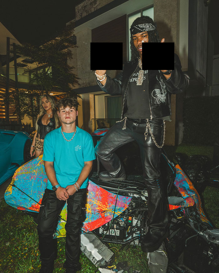 Young men including Jack Doherty posing by a colorful wrecked car at night, representing Jack Doherty and his rising net worth.