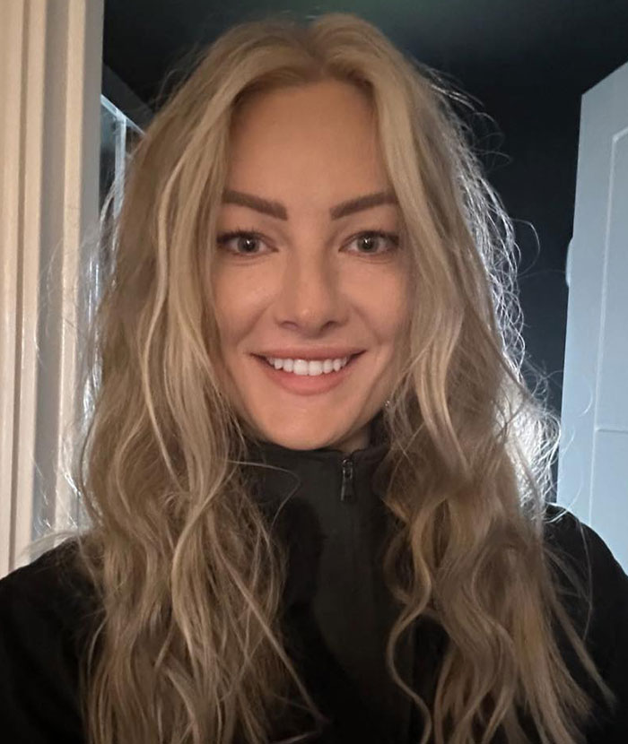 Smiling woman with long blonde hair, an experienced skydiver with over 400 flights, wearing a black jacket indoors. Smiling woman with long blonde hair, an experienced skydiver with over 400 flights, wearing a black jacket indoors.