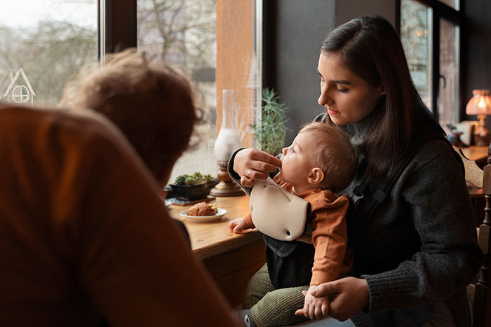 Traveling mom and dad sit by a window with their baby in a cozy restaurant, highlighting kindness from a Japanese waitress. Traveling mom and dad sit by a window with their baby in a cozy restaurant, highlighting kindness from a Japanese waitress.