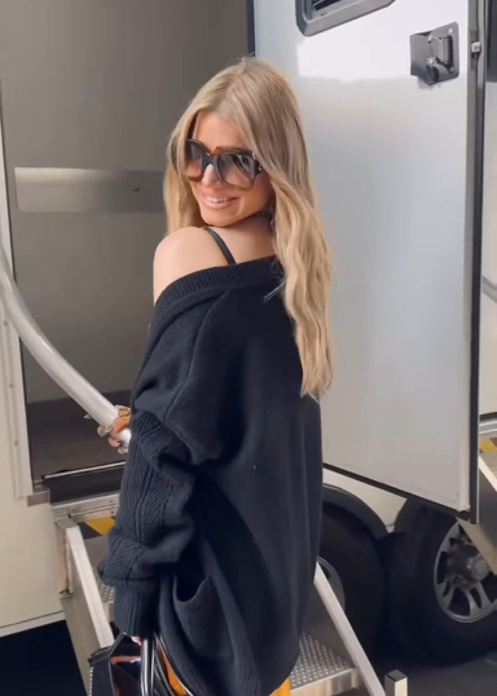 Jessica Simpson wearing sunglasses and a black sweater, smiling while boarding a trailer before live TV performance. Jessica Simpson wearing sunglasses and a black sweater, smiling while boarding a trailer before live TV performance.