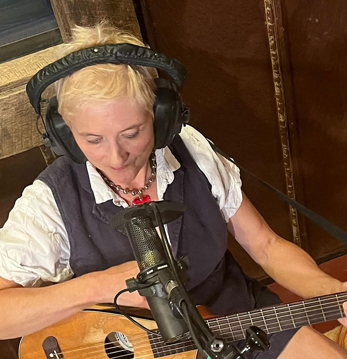 Singer Jill Sobule wearing headphones, playing guitar, recording music in a studio setting before mysterious house fire. Singer Jill Sobule wearing headphones, playing guitar, recording music in a studio setting before mysterious house fire.