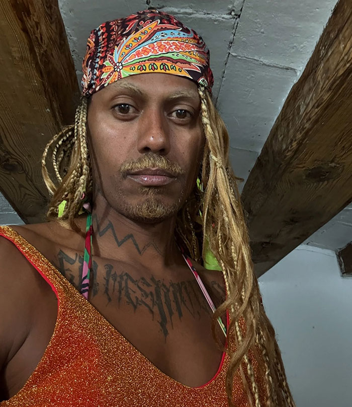 Person with long braided hair and a colorful headscarf wearing a sparkling top, breaking Cannes dress code with mass applause. Person with long braided hair and a colorful headscarf wearing a sparkling top, breaking Cannes dress code with mass applause.