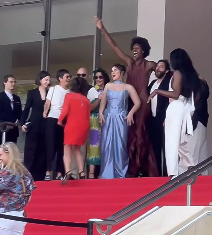 Star on red carpet at Cannes, revealing backside and breaking dress code, receiving applause from crowd. Star on red carpet at Cannes, revealing backside and breaking dress code, receiving applause from crowd.