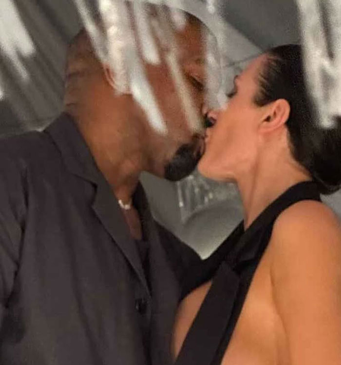 Bianca Censori in a revealing outfit kissing a man closely with a blurred background and soft lighting indoors. Bianca Censori in a revealing outfit kissing a man closely with a blurred background and soft lighting indoors.