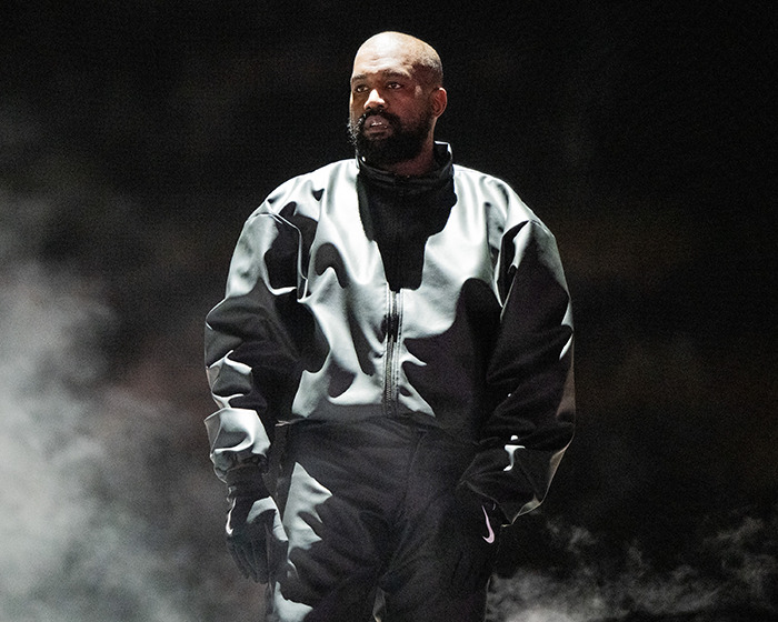 Kanye West wearing a dark outfit standing in smoky lighting, related to post about being subservient Bianca Censori master. Kanye West wearing a dark outfit standing in smoky lighting, related to post about being subservient Bianca Censori master.
