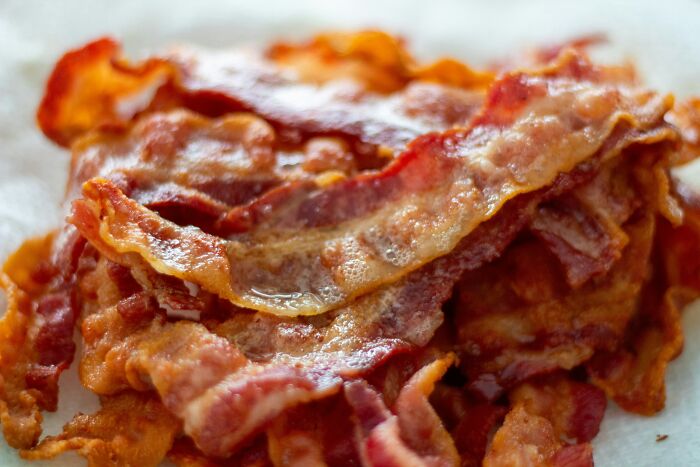 Crispy cooked bacon stacked on a paper towel, capturing the rich texture and savory appeal of unhinged parents diabolical snack.