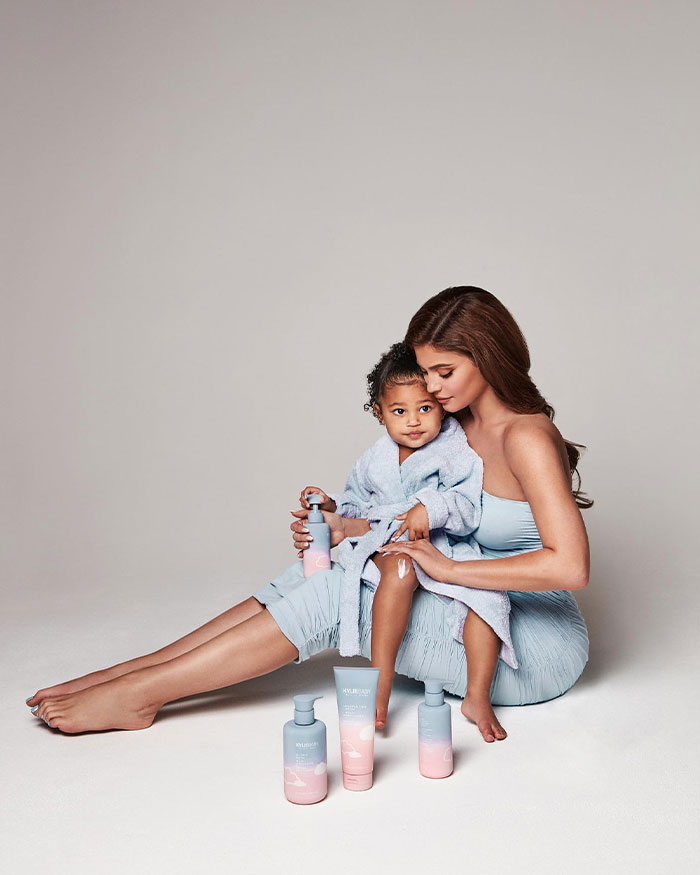 Kylie Jenner sitting with her child, applying skincare products, highlighting Kylie Jenner’s net worth and lifestyle.