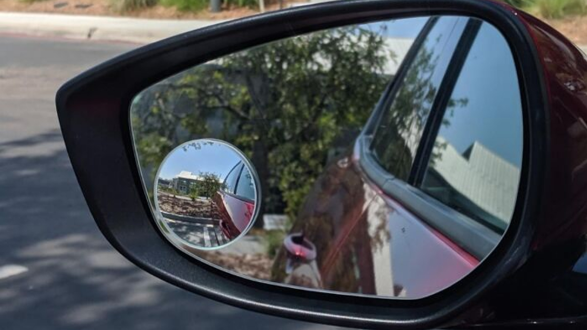 Car side mirror with an additional blind spot mirror installed to help people nail adulting safety while driving.