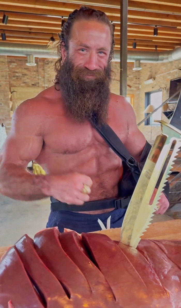 Muscular man with beard preparing extreme raw animal diet with large knife in rustic kitchen setting. Muscular man with beard preparing extreme raw animal diet with large knife in rustic kitchen setting.