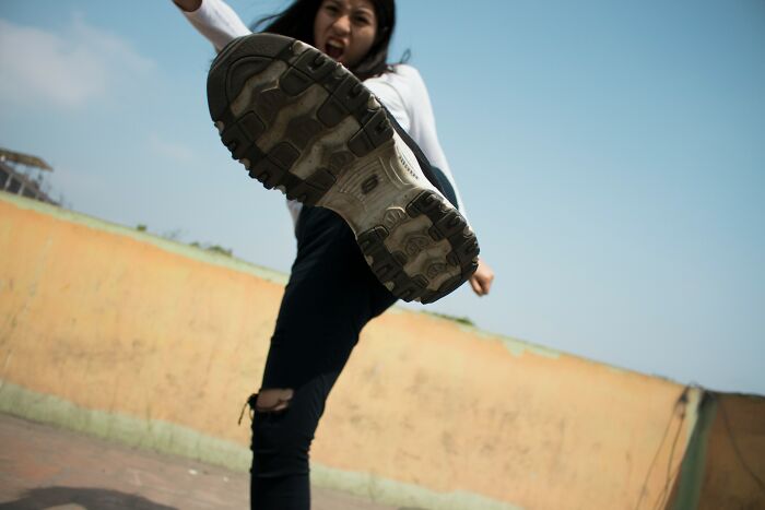 Young woman aggressively kicking toward the camera, illustrating morally questionable behavior related to netizens and piracy.