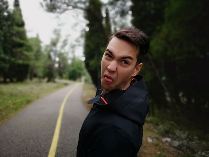 Young man outdoors grimacing with disgust on a forest path, representing mailman dumping pee in gardens and revenge.