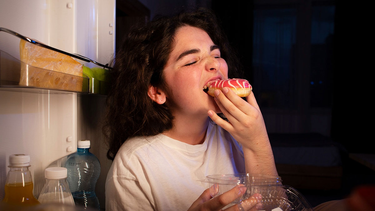 Teen daughter eating junk food from fridge at night, reacting to mom making kids pay for their own snacks.