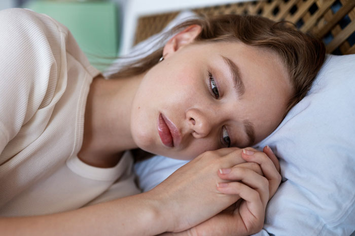 Teen daughter lying on bed looking upset after mom makes kids pay for their own junk food. Teen daughter lying on bed looking upset after mom makes kids pay for their own junk food.