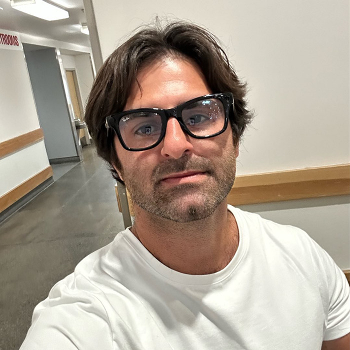 Man with glasses and light beard in hallway, related to hero confronting creepy influencer secretly filming woman with smart glasses. Man with glasses and light beard in hallway, related to hero confronting creepy influencer secretly filming woman with smart glasses.