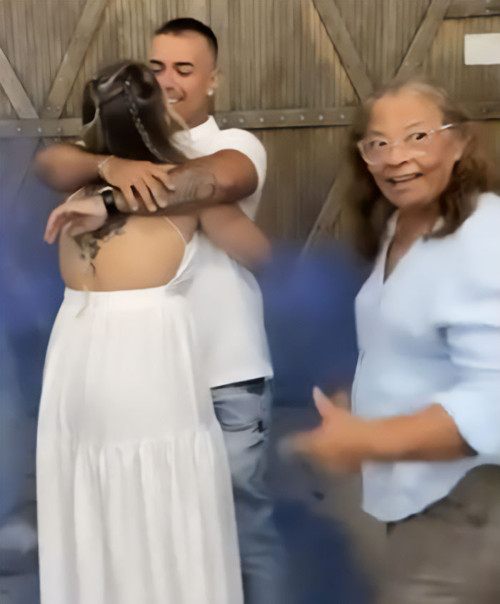 Man hugging wife during baby gender reveal while mom looks on, highlighting man pushes mom away controversy. Man hugging wife during baby gender reveal while mom looks on, highlighting man pushes mom away controversy.