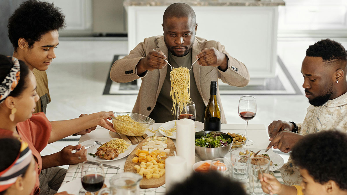 Family having a meal together with pasta and wine, highlighting conflict around parents forcing teen son to be vegan.