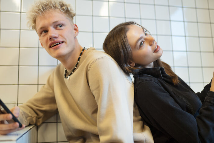 Young man and woman sitting back to back, illustrating lost friendships and ultimatums between male and female friends.