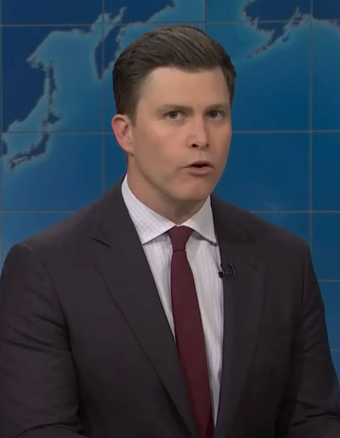 Male SNL cast member in a suit delivering a sketch on a news parody set during the show’s segment. Male SNL cast member in a suit delivering a sketch on a news parody set during the show’s segment.