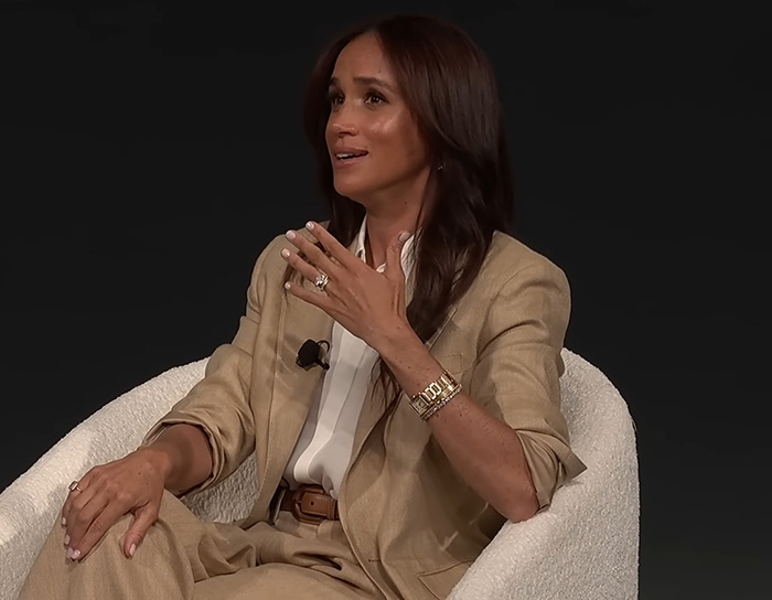 Meghan Markle speaking during an interview, wearing a beige suit, related to wedding caterer and Queen Elizabeth intervention. Meghan Markle speaking during an interview, wearing a beige suit, related to wedding caterer and Queen Elizabeth intervention.