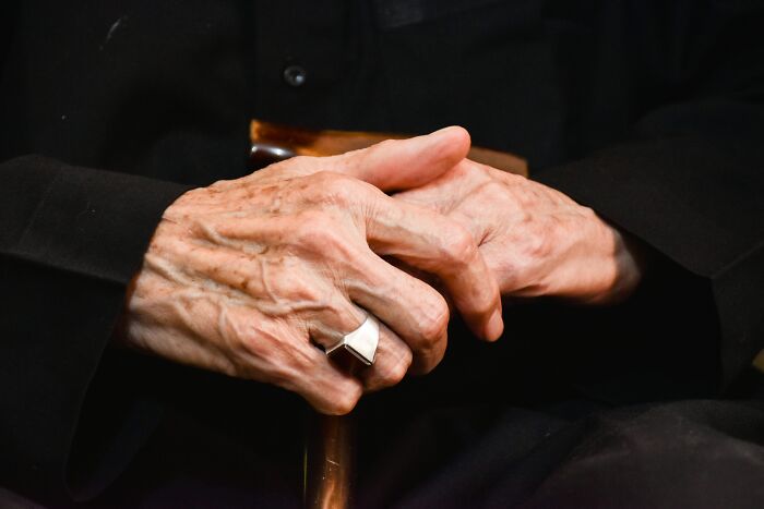 Close-up of elderly hands clasping a cane, illustrating morally questionable actions accepted by some netizens.