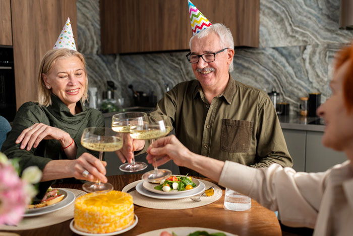 Older couple wearing party hats toasting glasses at a fancy restaurant celebrating son’s birthday with expected bill for eight people. Older couple wearing party hats toasting glasses at a fancy restaurant celebrating son’s birthday with expected bill for eight people.