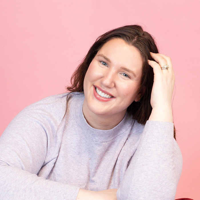 Smiling woman in a lavender sweater against a pink background, representing a mom waking from surgery unprepared for kids born. Smiling woman in a lavender sweater against a pink background, representing a mom waking from surgery unprepared for kids born.