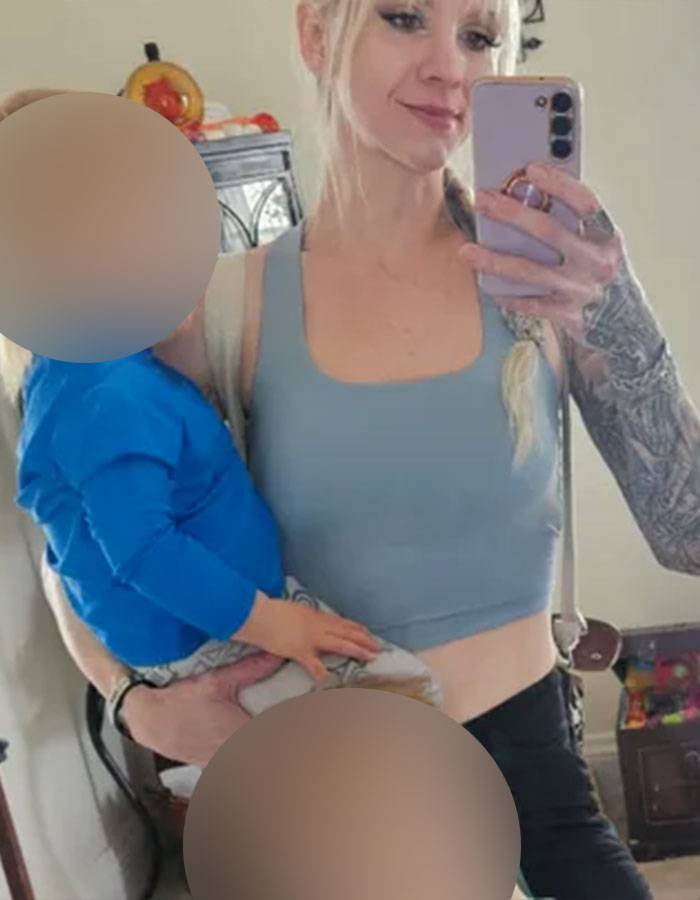 Woman with tattoos taking a mirror selfie holding a young child in a blue shirt, related to racist playground incident raising funds. Woman with tattoos taking a mirror selfie holding a young child in a blue shirt, related to racist playground incident raising funds.