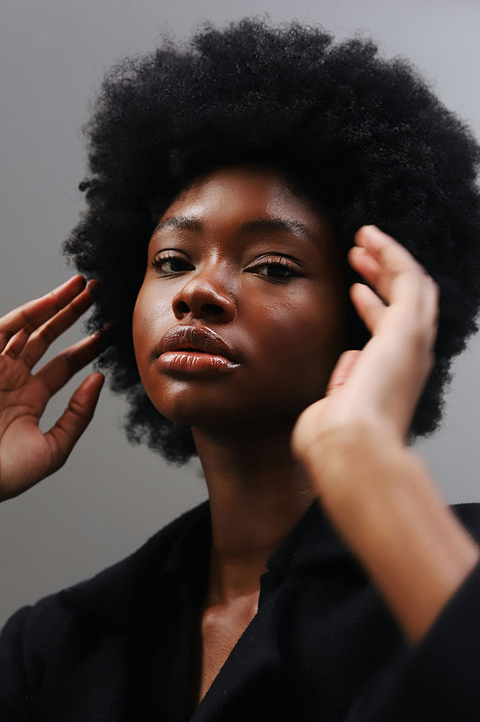 Portrait of a confident woman with natural hair exploring concepts of beauty and science in a minimalistic setting. Portrait of a confident woman with natural hair exploring concepts of beauty and science in a minimalistic setting.