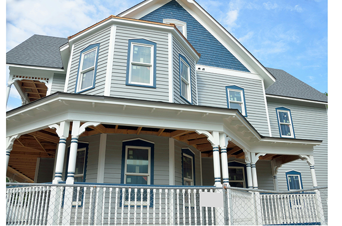 Modern two-story house with a sturdy white fence intact in front, showcasing neighbor fence durability in clear weather.