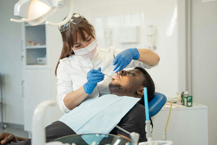 Dentist examining patient’s teeth in clinic, highlighting issues related to man telling girlfriend his teeth aren’t real after years. Dentist examining patient’s teeth in clinic, highlighting issues related to man telling girlfriend his teeth aren’t real after years.