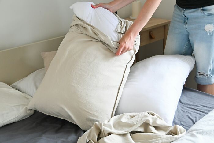 Person adjusting pillow on bed, highlighting tiny thing made trip better by improving comfort during travel.