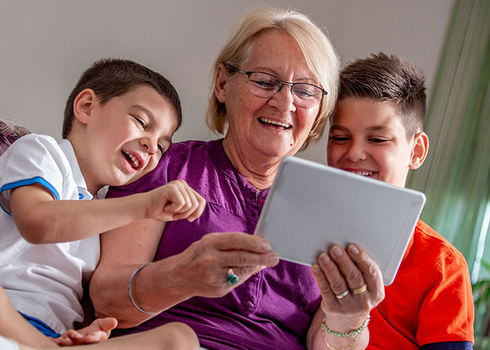 Grandmother spending time with kids using a tablet, highlighting concerns about kids being fed fast food by MIL. Grandmother spending time with kids using a tablet, highlighting concerns about kids being fed fast food by MIL.